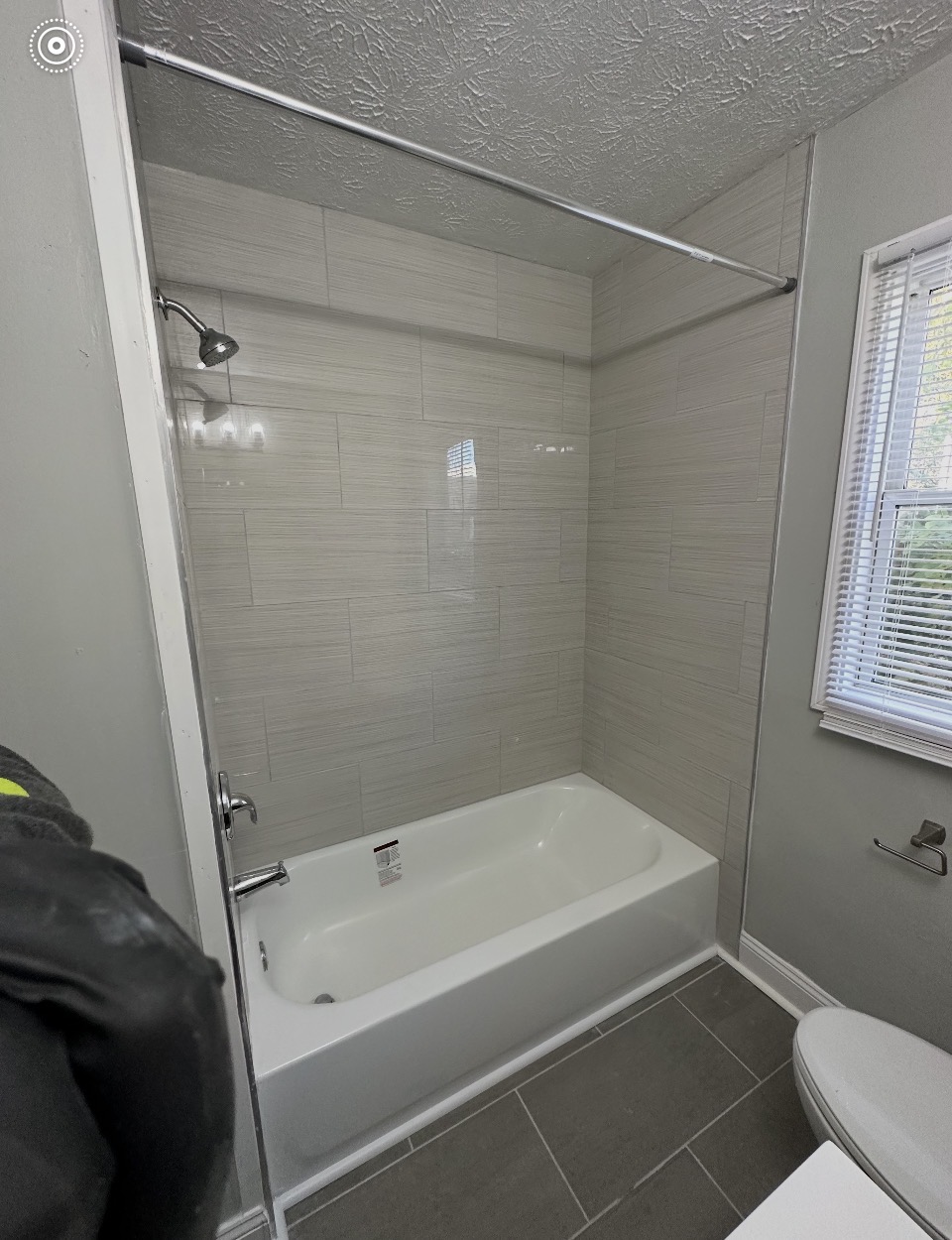 Remodeled Indianapolis bathroom with new white tub, light linen-look tile surround, and slate-look porcelain floor tile