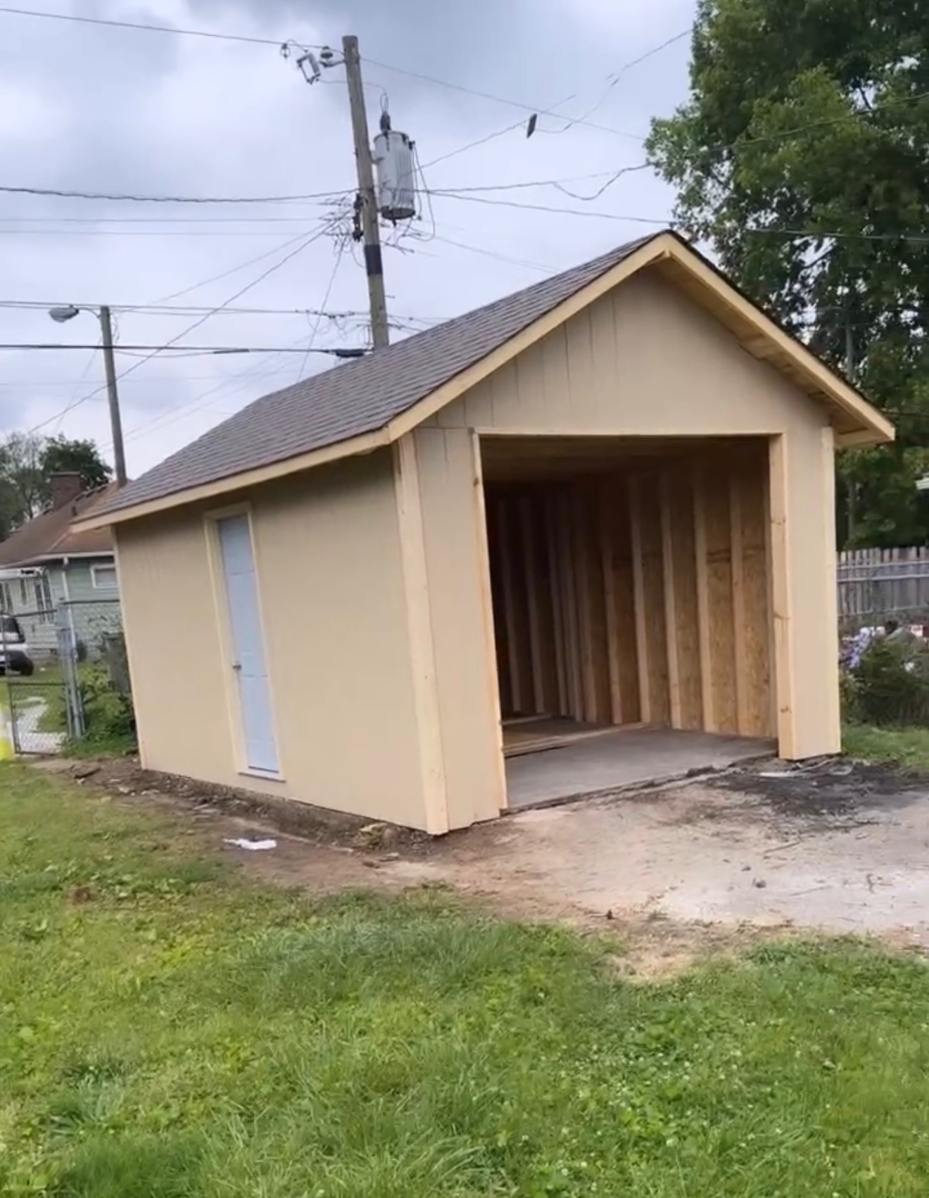 Completed detached Indianapolis garage with shingled gable roof, tan siding, trim, and finished service door